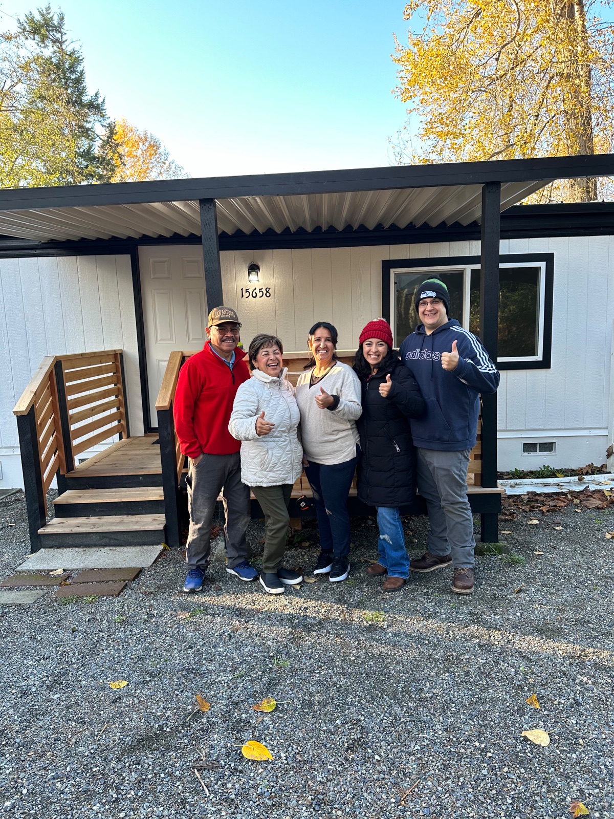 Family giving thumbs up in front of their new home