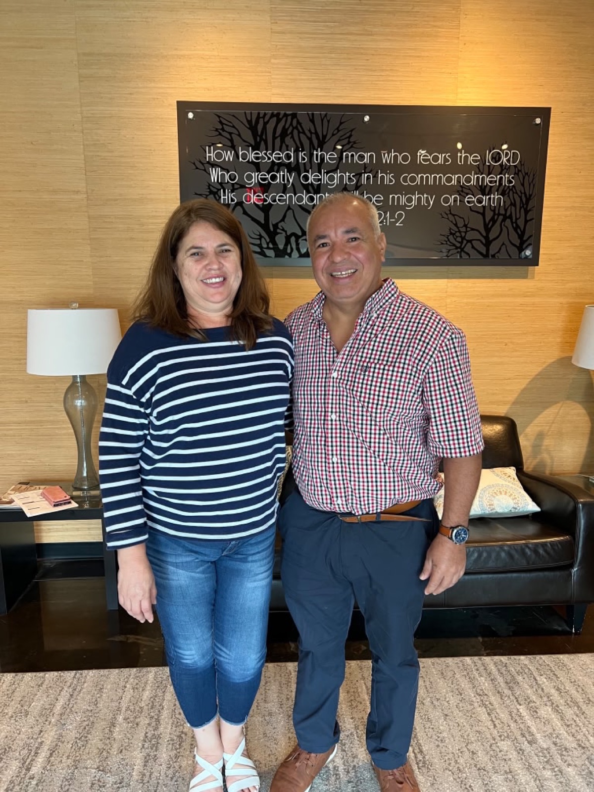 Couple smiling at closing table in front of inspirational wall art, celebrating their new home purchase